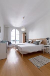 a white bedroom with a large bed and a table at Bel appartement bourgeois au centre-ville de Biarritz in Biarritz