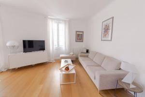 a white living room with a couch and a tv at Bel appartement bourgeois au centre-ville de Biarritz in Biarritz