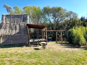 a wooden shed with a bench in a field at Cabaña Pirayú in Oliveros