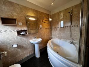 a bathroom with a tub and a sink and a toilet at Herriots Hotel in Skipton