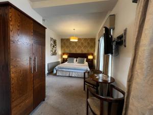a bedroom with a bed and a table and a desk at Herriots Hotel in Skipton