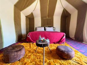 a bedroom with a bed and two ottomans at Merzouga Camp & Desert Activities in Merzouga