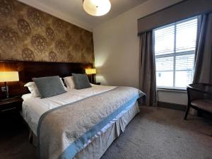 Un dormitorio con una cama grande y una ventana en Herriots Hotel, en Skipton