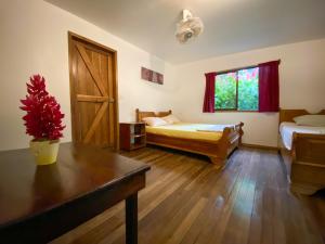 Cette chambre comprend 2 lits, une table et une fenêtre. dans l'établissement La Ruka Hostel, à Puerto Viejo