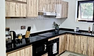 eine Küche mit Holzschränken und einer schwarzen Arbeitsplatte in der Unterkunft InstaHomes by Tru - Villa in Blantyre