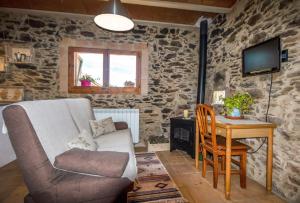 a living room with a couch and a table and a television at Apartamento duplex rural con chimenea y vistas panorámicas desde la cama in San Martín Sacalm