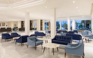 a lobby with blue chairs and tables and windows at Royal Azur Thalassa in Hammamet