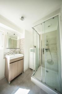 een badkamer met een glazen douche en een wastafel bij L'Indépendant in Nemours