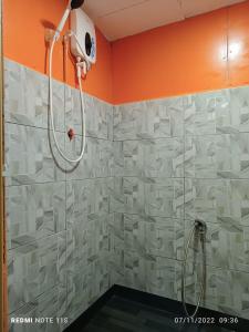a shower in a bathroom with an orange wall at Juara Ocean Chalet in Kampong Juara