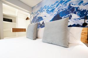 - une chambre avec un lit blanc orné d'une fresque murale de montagne dans l'établissement Cilene del Fuego Suites & Spa, à Ushuaia