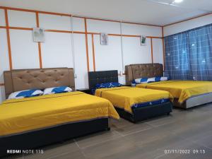two beds in a room with yellow beds in it at Juara Ocean Chalet in Kampong Juara