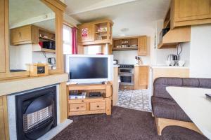 a living room with a couch and a television in a caravan at 6 Berth Caravan For Hire At Martello Beach Holiday Park In Essex Ref 29017y in Clacton-on-Sea