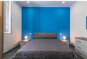 een slaapkamer met een blauwe muur en een bed bij La casa di Alessandro in Noto