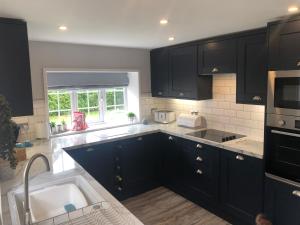 a kitchen with black cabinets and a sink at Old Smithy Cottage in Great Singleton