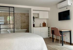 ein Schlafzimmer mit einem Bett und einem Tisch sowie ein Badezimmer in der Unterkunft Madame Imagine, Lodges & SPA Epinal in Épinal