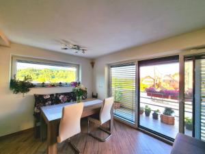 - une salle à manger avec une table, des chaises et 2 fenêtres dans l'établissement GARTNAR HOME -Hiška s pridihom domačnosti in pogledom na hribe., à Radovljica