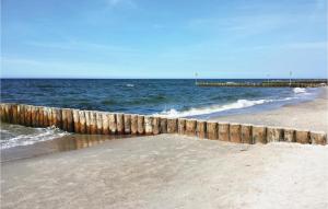 einen Sandstrand mit einem Pier im Ozean in der Unterkunft Beautiful Home In Ustronie Morskie in Ustronie Morskie
