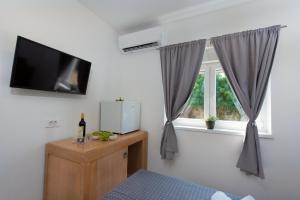 a room with a tv and a window with curtains at Hotel Potpican in Potpićan