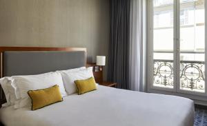 Crowne Plaza Paris République, an IHG Hotel في باريس: غرفة نوم بسرير كبير وبها وسادتين ونافذة