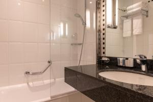 uma casa de banho com um lavatório, um chuveiro e uma banheira em Crowne Plaza Paris République, an IHG Hotel em Paris