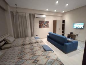 een slaapkamer met een groot bed en een blauwe bank bij Eco Inn Sherook993g2 Studio in Madīnat ash Shurūq