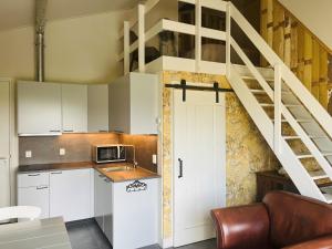 a kitchen with white cabinets and a spiral staircase at Doornvlak - dicht bij strand en duinen! in Castricum