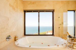 baño con bañera grande y ventana en Aqua Terra Boutique Guesthouse, en Simonʼs Town