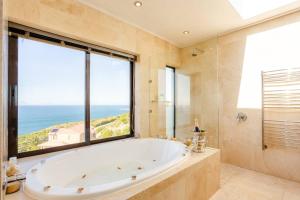 a bath tub in a bathroom with a large window at Aqua Terra Boutique Guesthouse in Simonʼs Town
