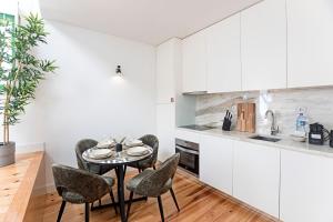 cocina con armarios blancos, mesa y sillas en D. João IV Apartments by LovelyStay, en Oporto
