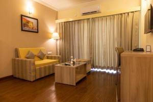 Starlit Suites Tirupati في تيروباتي: غرفة معيشة مع أريكة وكرسي
