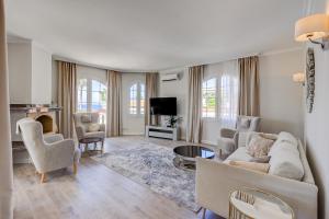 a living room with a couch and chairs and a tv at Luxury villa El Duque Ocean View in Adeje