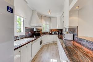 a kitchen with white cabinets and a sink and a microwave at Luxury villa El Duque Ocean View in Adeje