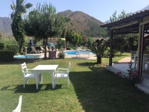 una mesa y sillas en un patio con piscina en Ada Adrasan Hotel en Kumluca