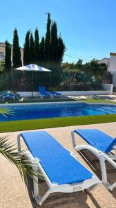 2 sillones azules y blancos junto a una piscina en La Casa Arboleas, en Arboleas