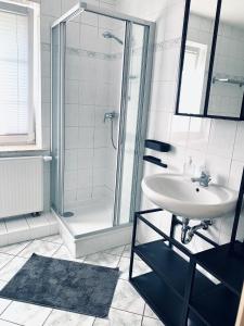 a white bathroom with a sink and a shower at Apartment im Gästehaus Matzmühle Ruhland (6-8 P.) in Ruhland