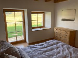 a bedroom with a bed and a dresser and windows at Brasel in La Brévine