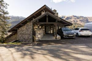 a building with two cars parked in front of it at Les GRANDS SORBIERS à Méribel - Charmant studio situé à 2 pas des pistes & du centre de Méribel in Les Allues