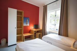 Schlafzimmer mit roten Wänden, einem Bett und einem Fenster in der Unterkunft Schillinger-Berlin - dance, sleep, repeat! in Berlin