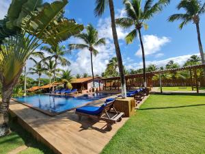 a resort swimming pool with lounge chairs and palm trees at Pousada Praia das Ondas - Pé na areia in Itacimirim