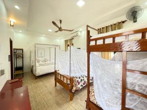 a bedroom with two bunk beds and a ceiling fan at Phong Nha Farmstay in Phong Nha