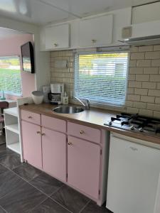 a kitchen with pink cabinets and a sink at Stacaravan 85 Recreatiepark De Tien Heugten. in Schoonloo