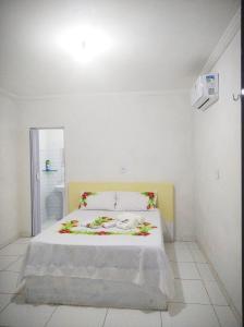 a white bedroom with a bed with flowers on it at Mila chalé in Cruz