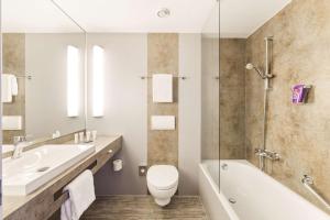 a bathroom with a sink and a toilet and a bath tub at Park Inn by Radisson Dresden in Dresden