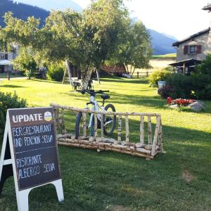 ein Fahrrad, das neben einem Schild im Hof parkt in der Unterkunft Albergo Ristorante Selva in Poschiavo