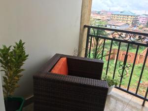 una panca marrone di vimini seduta su un balcone di J&R - Lovely two bedroom apartment in Jinja. a Jinja
