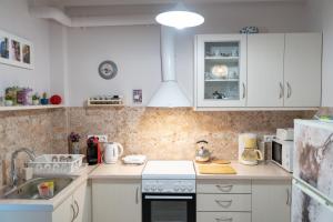 uma cozinha com armários brancos e um forno de fogão branco em Metaxourgeio metro st. 2 bedrms 4 pers. apartment. em Atenas