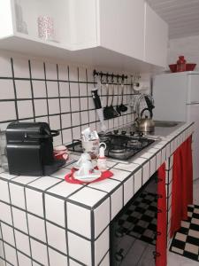 a white tiled kitchen with a stove top oven at Mamà Apartment in Augusta