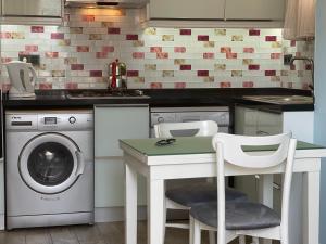 uma cozinha com uma máquina de lavar roupa e uma mesa com cadeiras em X SUITE APART em Fethiye