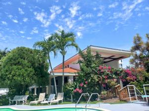 a house with a swimming pool and palm trees at Casa Aly in Santiago de los Caballeros