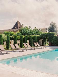 a pool with lounge chairs and a building in the background at Gîtes du Château Mont d'Onel in Couze-et-Saint-Front